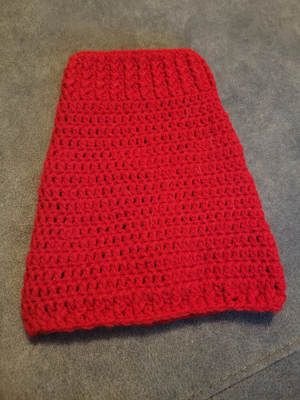 Red crocheted puppy sweater on gray surface