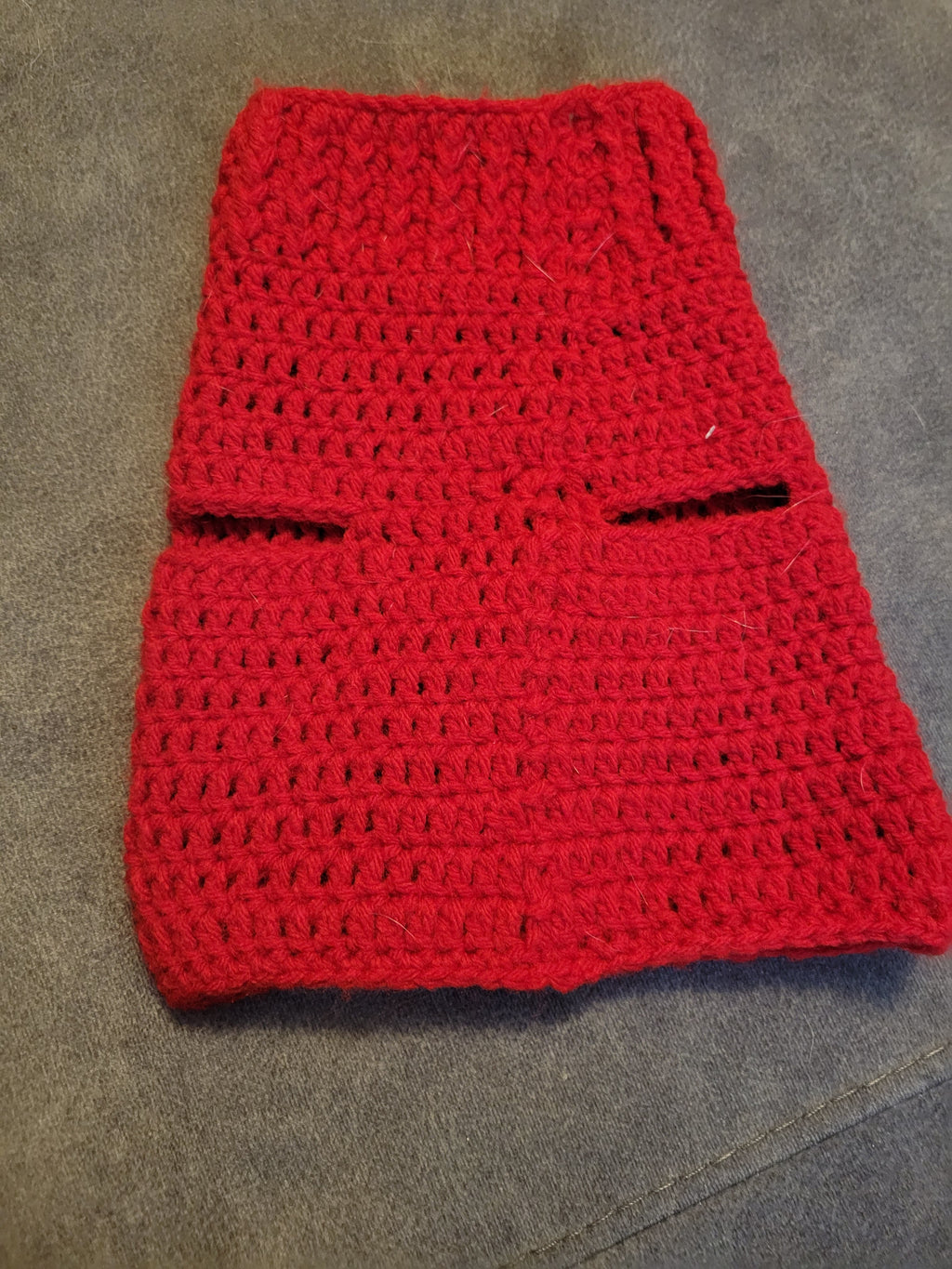 Red knitted puppy sweater photographed on gray fabric.